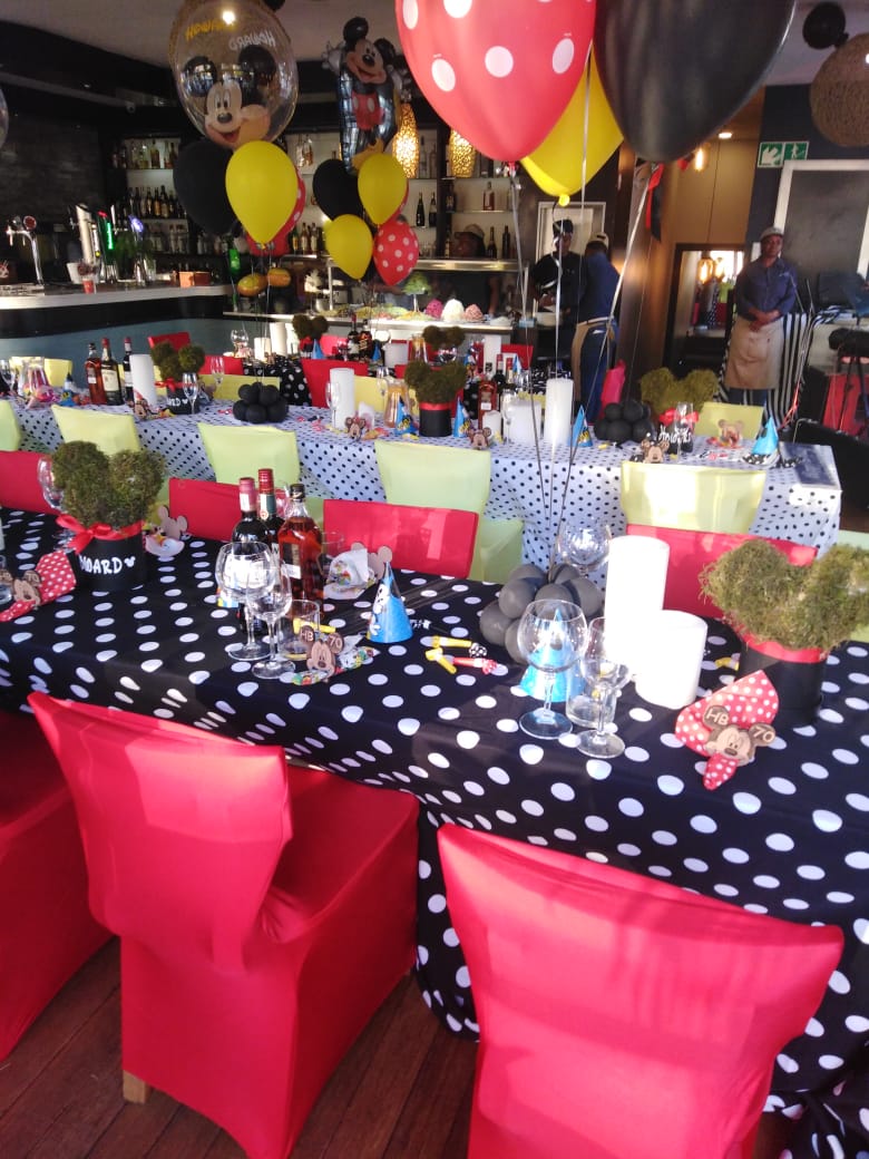 Party table set with red chairs and a bar behind